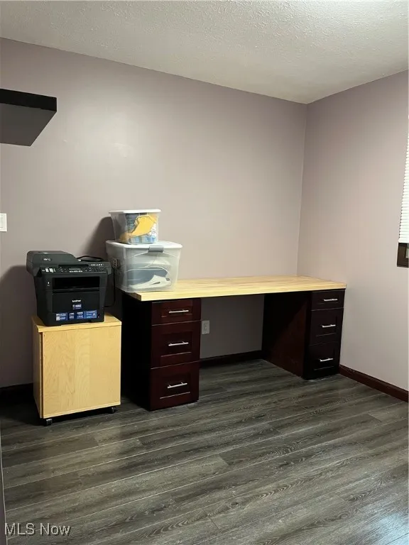 Unfurnished office with dark wood-type flooring and baseboards