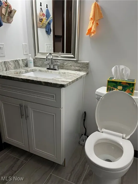 Bathroom with marble look tiles, toilet, and vanity