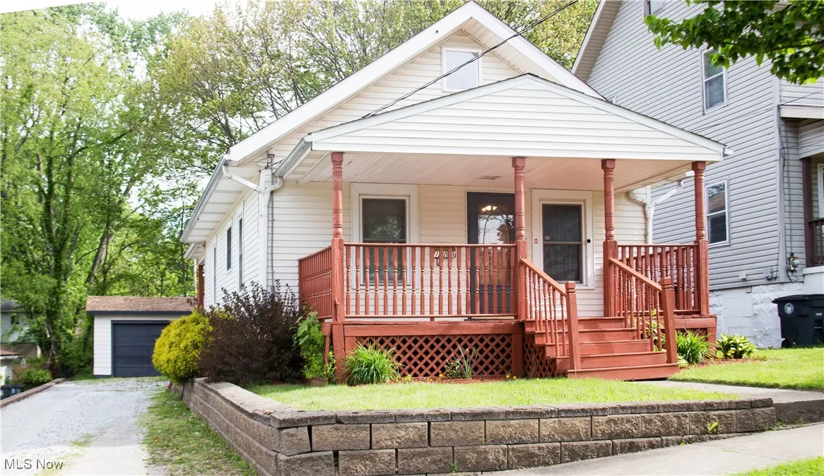 View of front of property featuring covered porch, an outbuilding, and a garage
