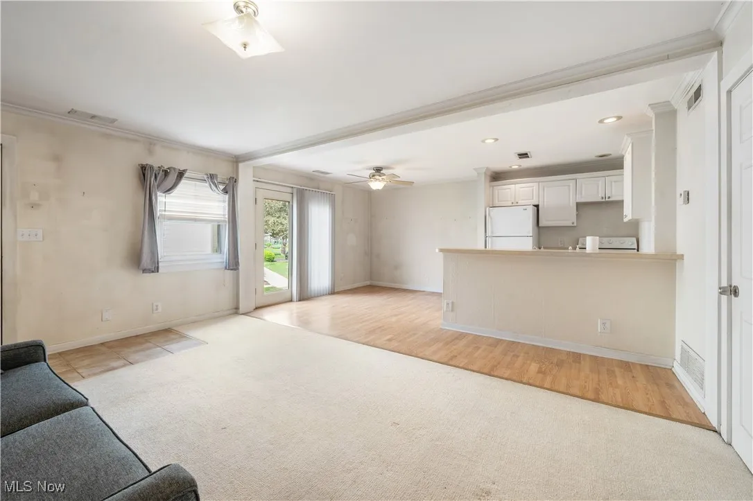 Unfurnished living room with light carpet, baseboards, ornamental molding, recessed lighting, and a ceiling fan