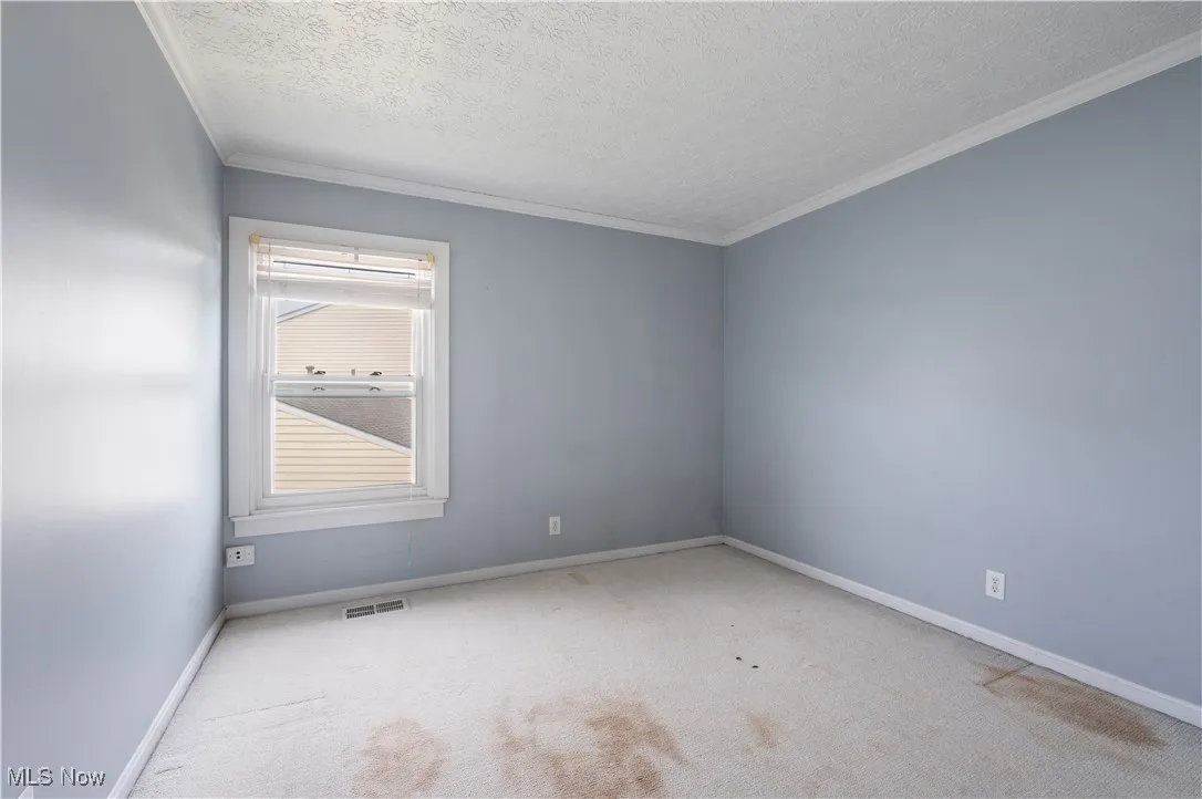 Carpeted bedroom featuring ornamental molding, baseboards, and a textured ceiling