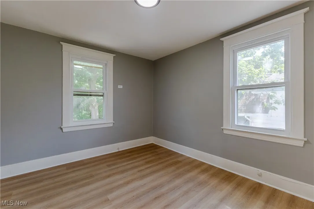 Unfurnished room featuring healthy amount of natural light, light wood-style flooring, and baseboards
