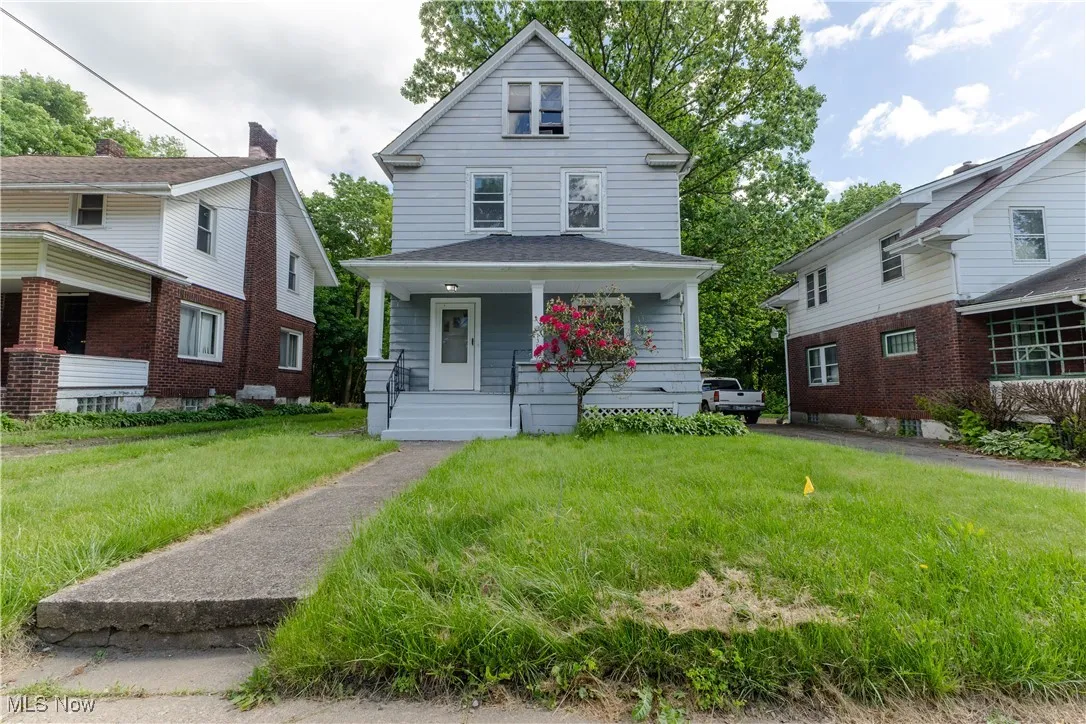 Traditional style home with covered porch and a front lawn