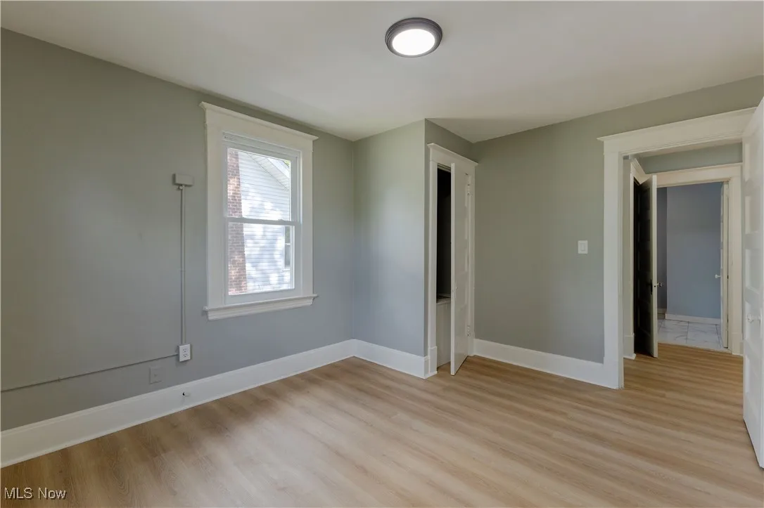 Unfurnished room featuring light wood finished floors and baseboards