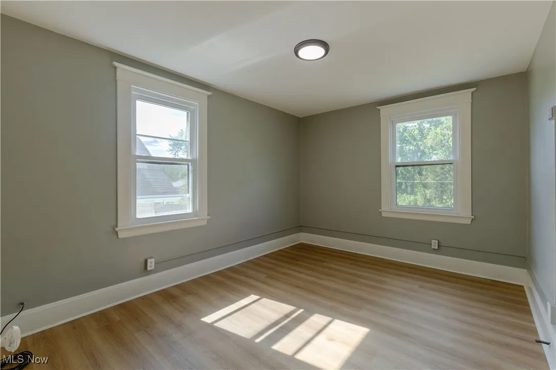 Unfurnished room featuring healthy amount of natural light, light wood-style floors, and baseboards