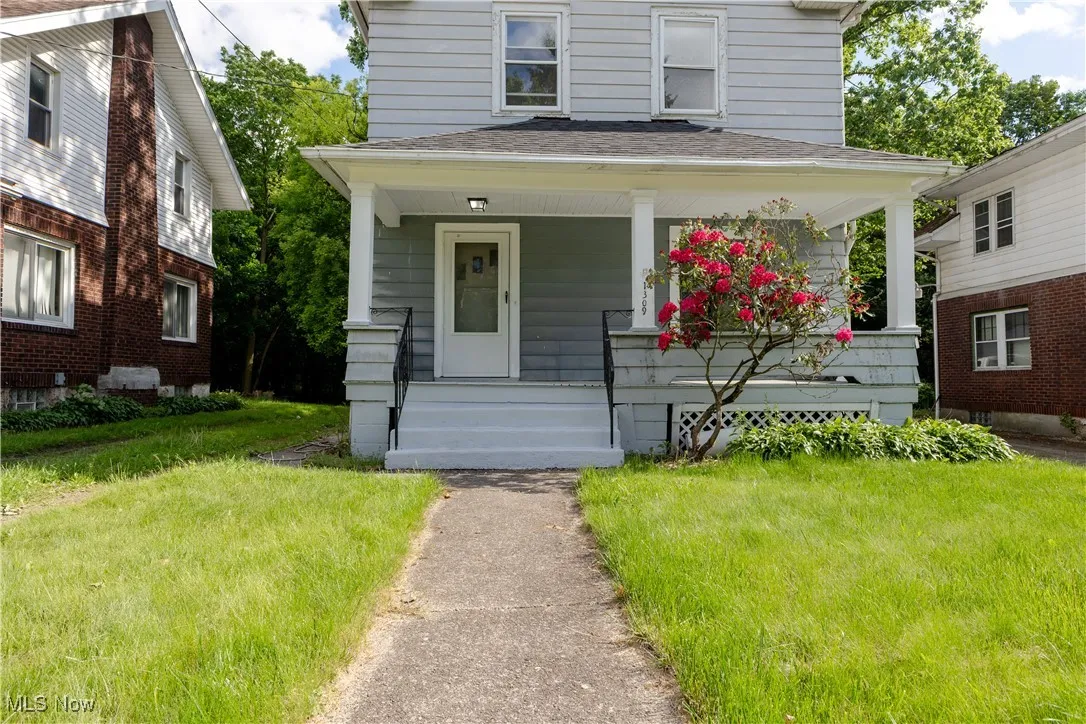 American foursquare style home with a porch, roof with shingles, and a front lawn