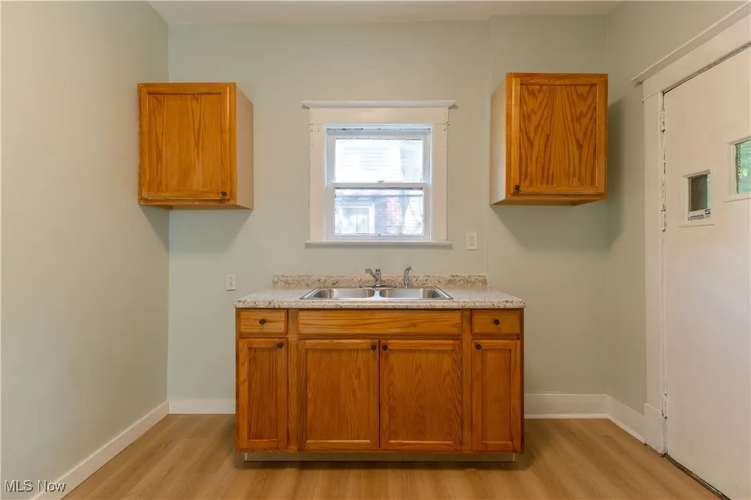 Kitchen featuring a sink, light wood-type flooring, light countertops, and brown cabinetry