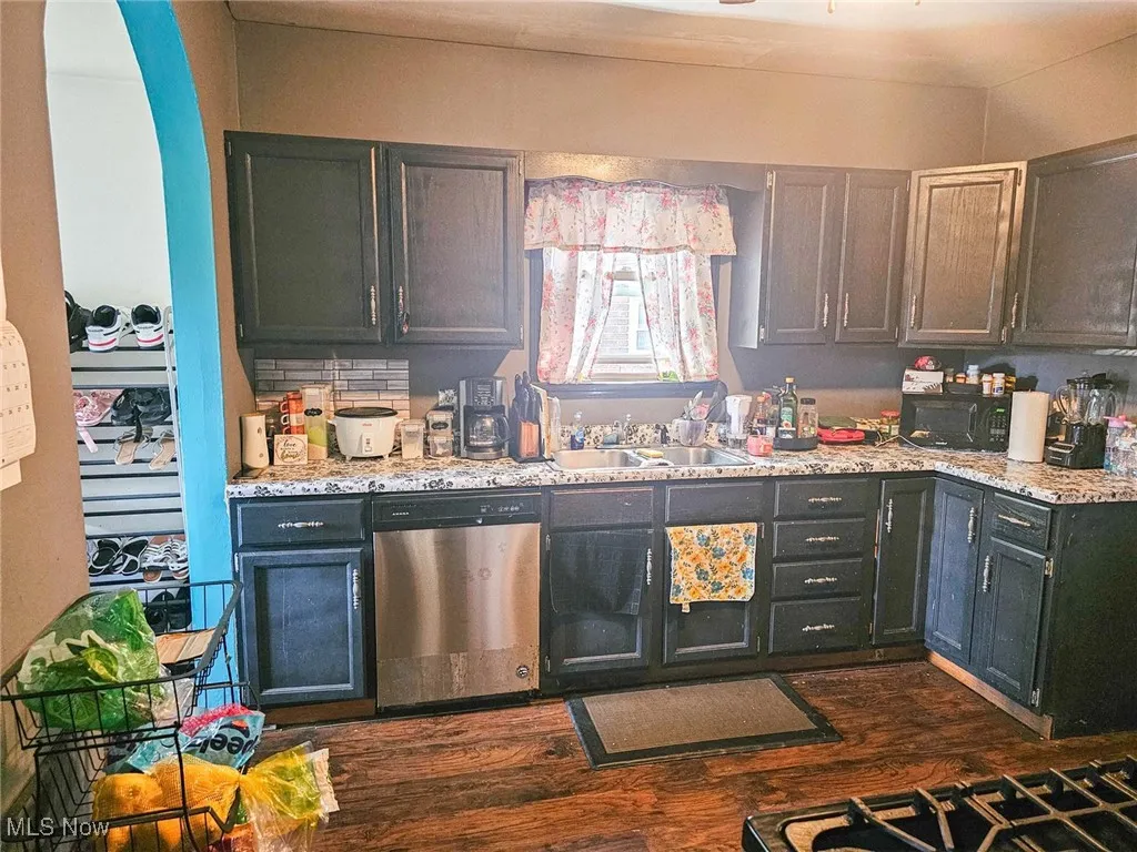 Kitchen with dishwasher, a sink, dark wood-type flooring, and black microwave