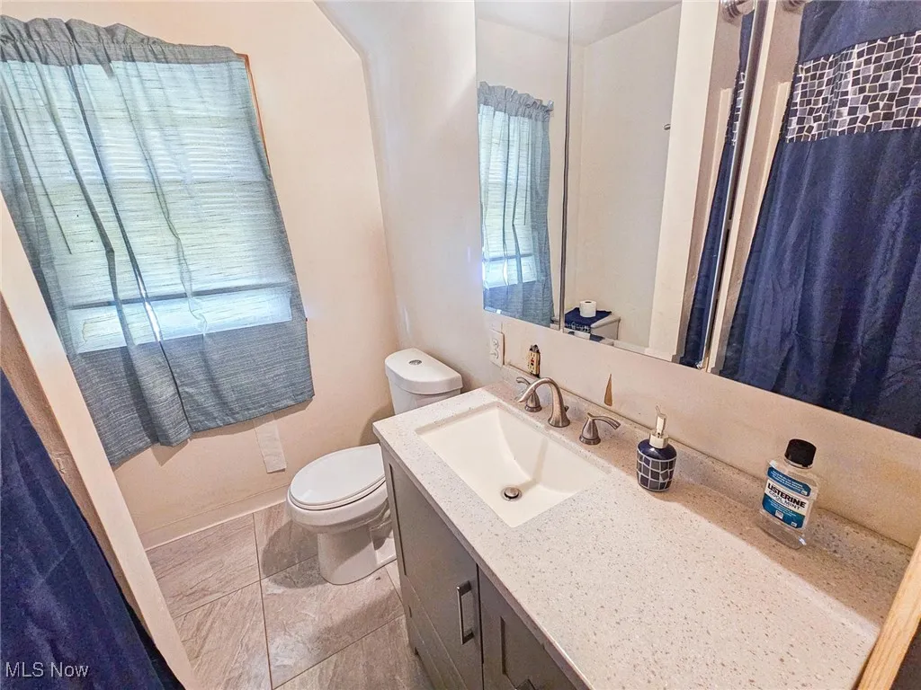 Bathroom with toilet, vanity, and baseboards