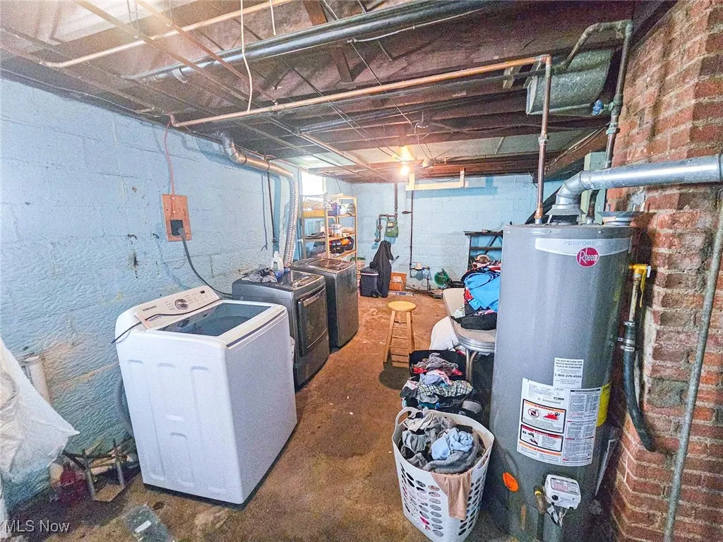 Unfinished basement featuring water heater and separate washer and dryer