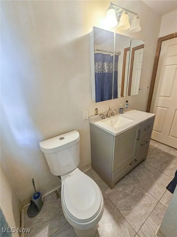 Full bath featuring toilet, vanity, and a shower with shower curtain