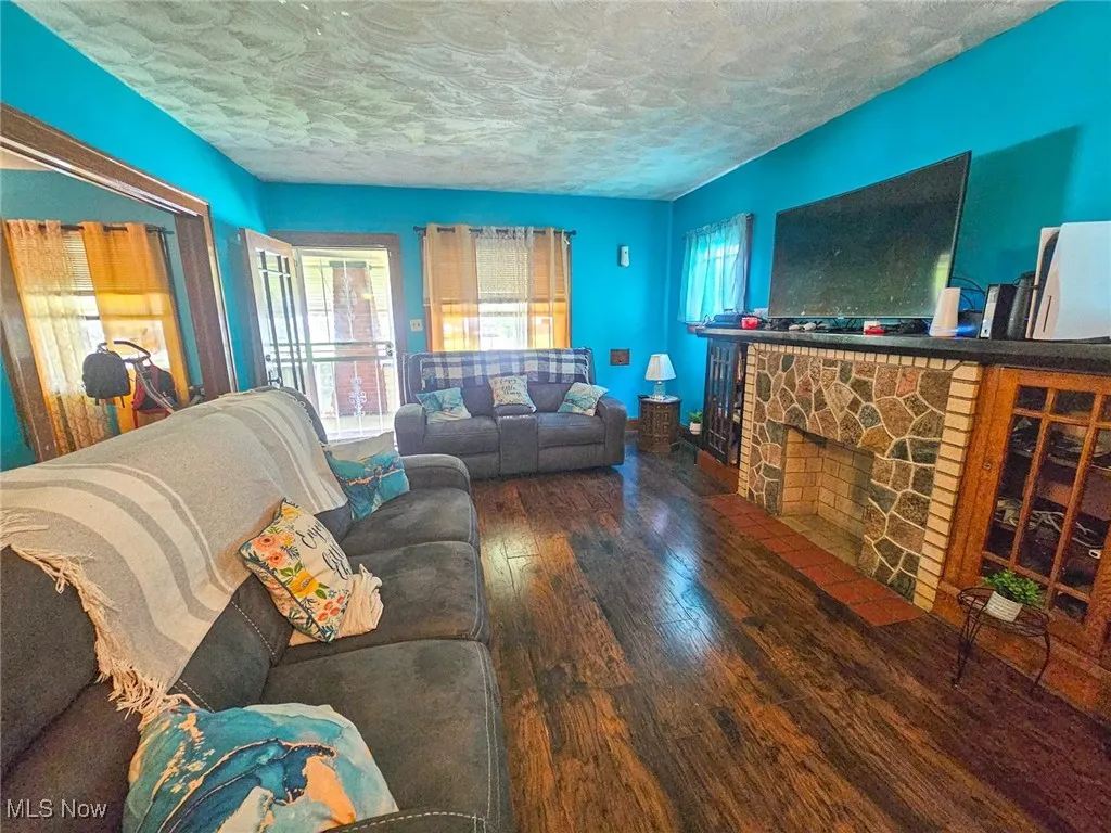 Living room featuring hardwood / wood-style floors, a textured ceiling, and a fireplace