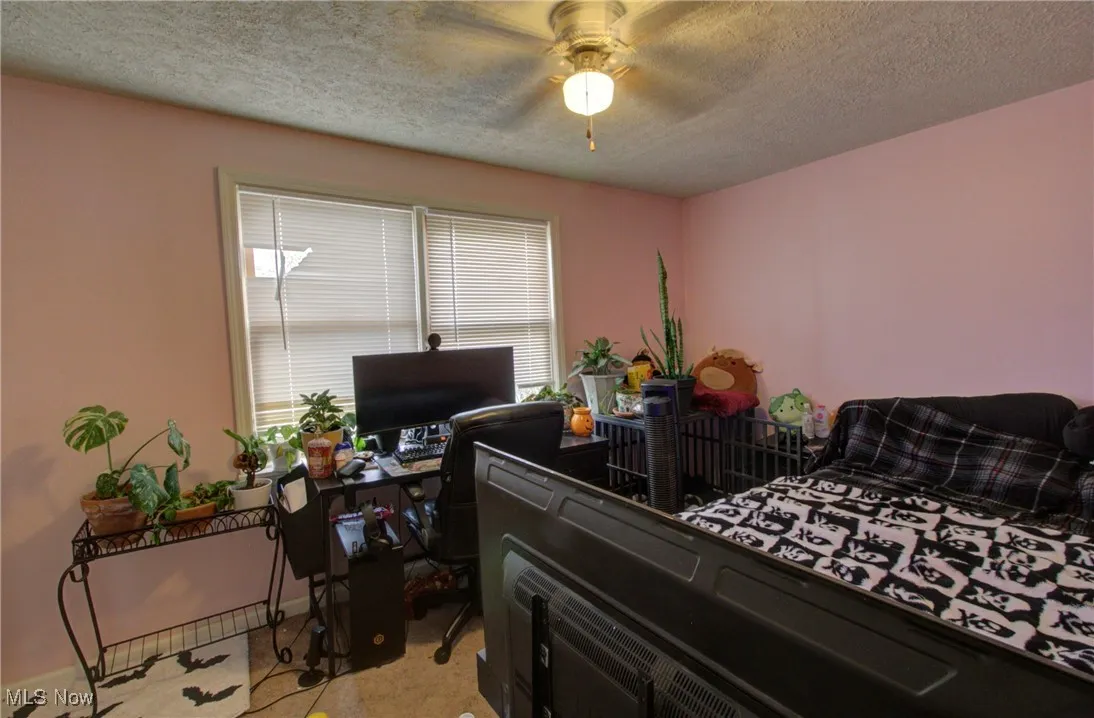 Bedroom featuring a textured ceiling, an office area, and a ceiling fan