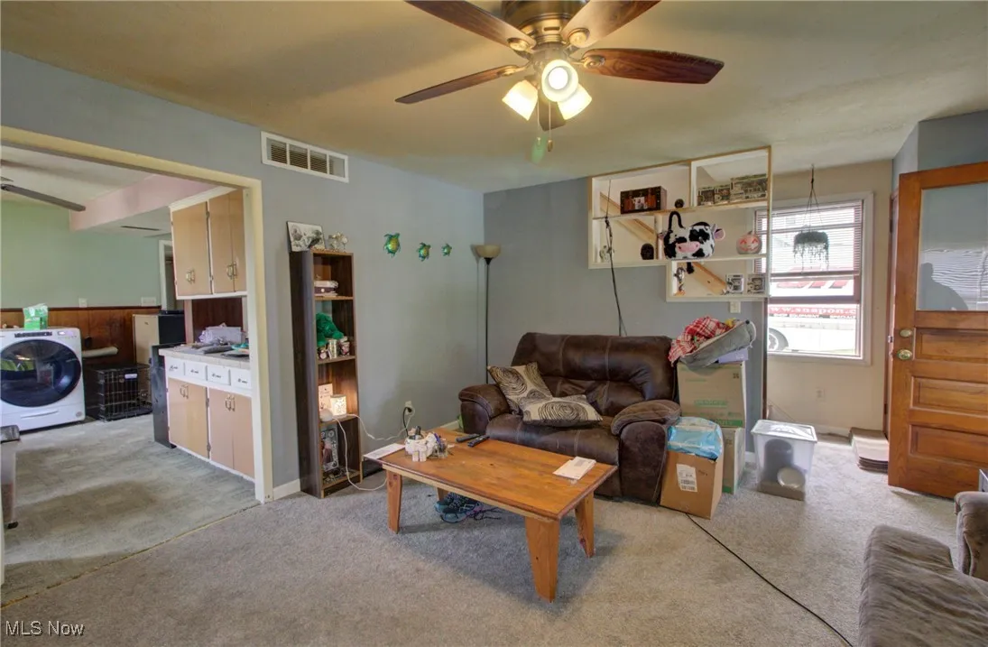 Living area with washer / dryer, light carpet, and a ceiling fan