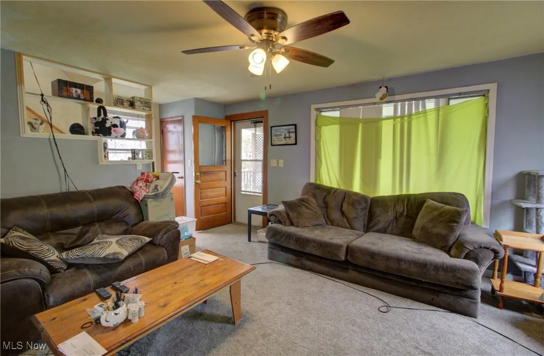 Carpeted living area with ceiling fan