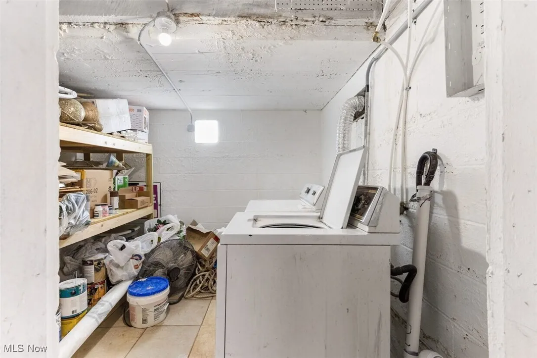 Laundry area with washer and clothes dryer and concrete block wall