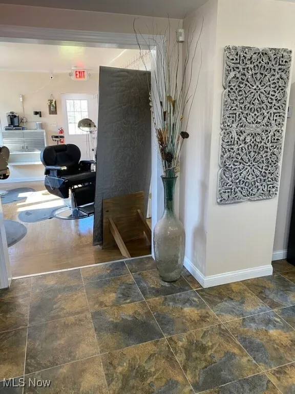 Hall featuring stone tile flooring and baseboards