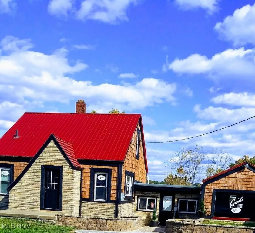 View of front of property with a chimney, stone siding, and metal roof