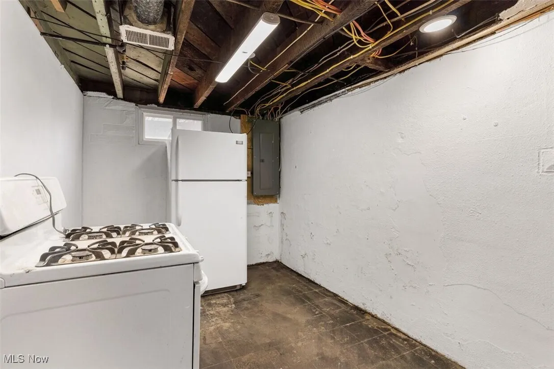 Basement with freestanding refrigerator and electric panel