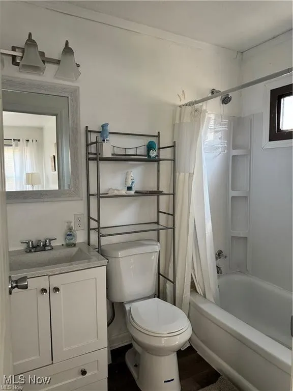 Full bath with toilet, shower / bath combo, vanity, and wood finished floors