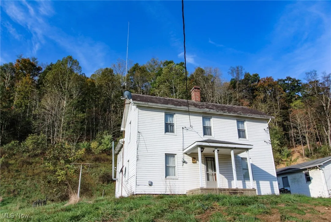 View of front facade featuring a chimney and a porch