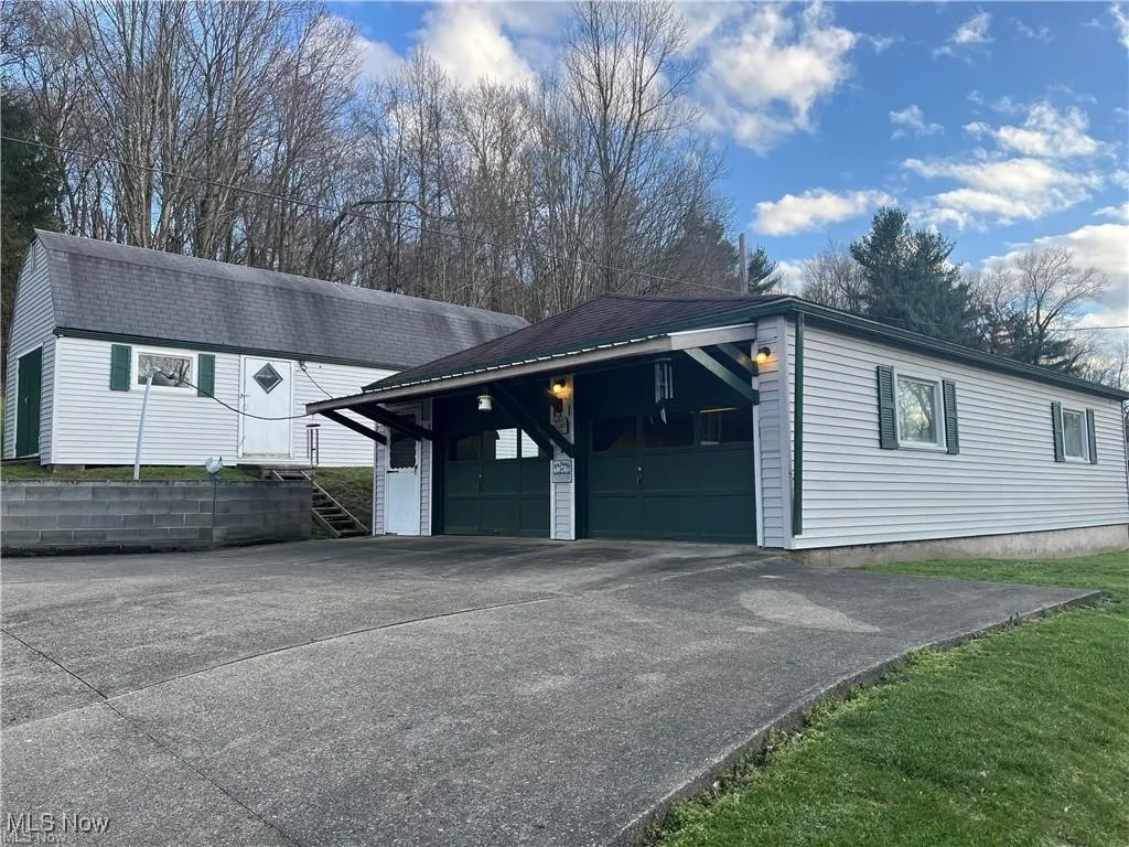 View of property exterior featuring driveway, a garage, and an outbuilding