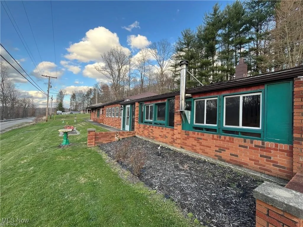 View of home's exterior featuring brick siding, a yard, and a chimney