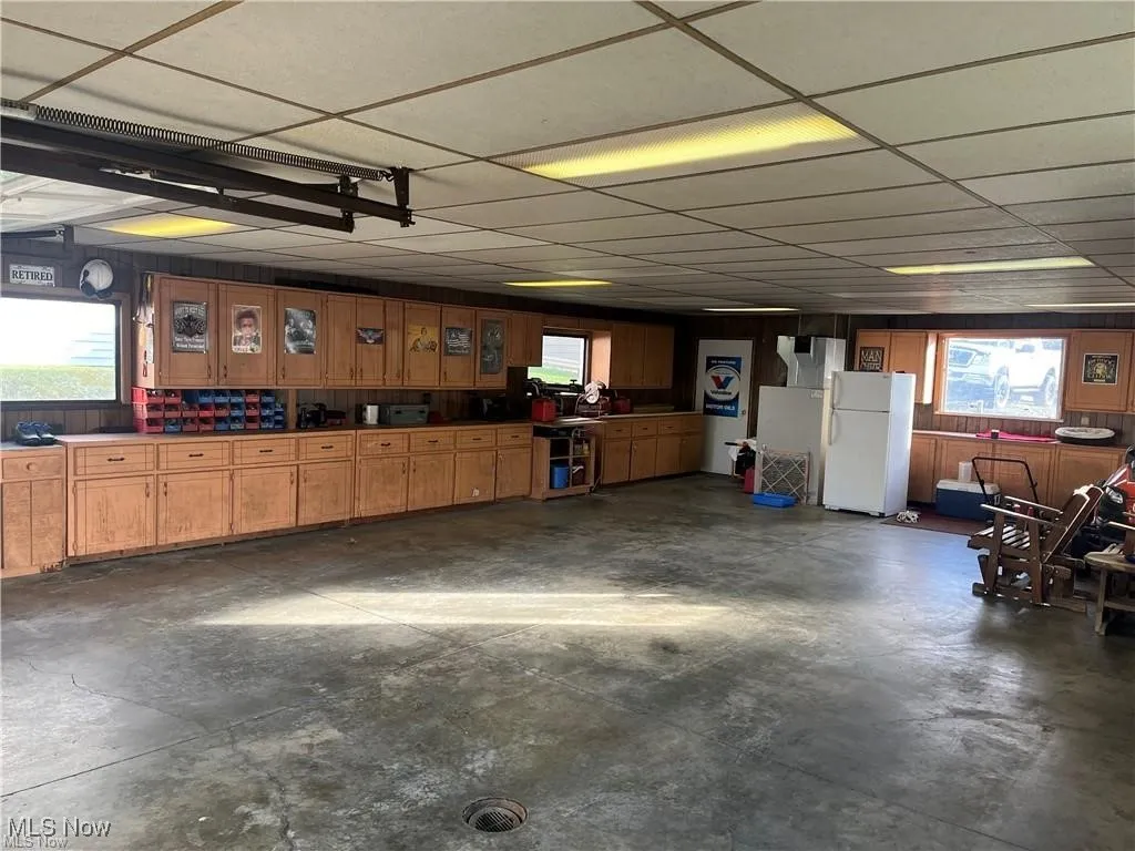Garage featuring freestanding refrigerator and wooden walls