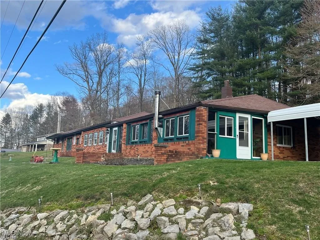 View of front of property featuring a chimney, brick siding, and a front lawn