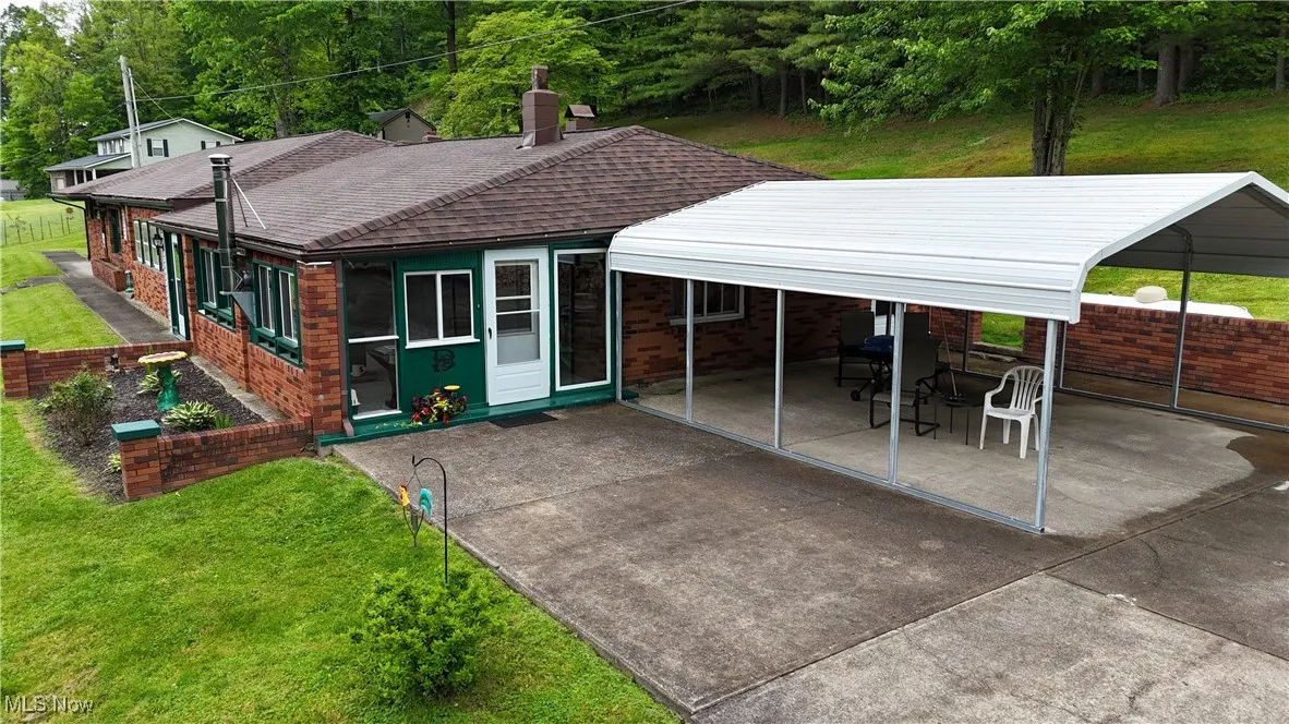 View of front facade with roof with shingles, a patio, a front yard, concrete driveway, and a carport
