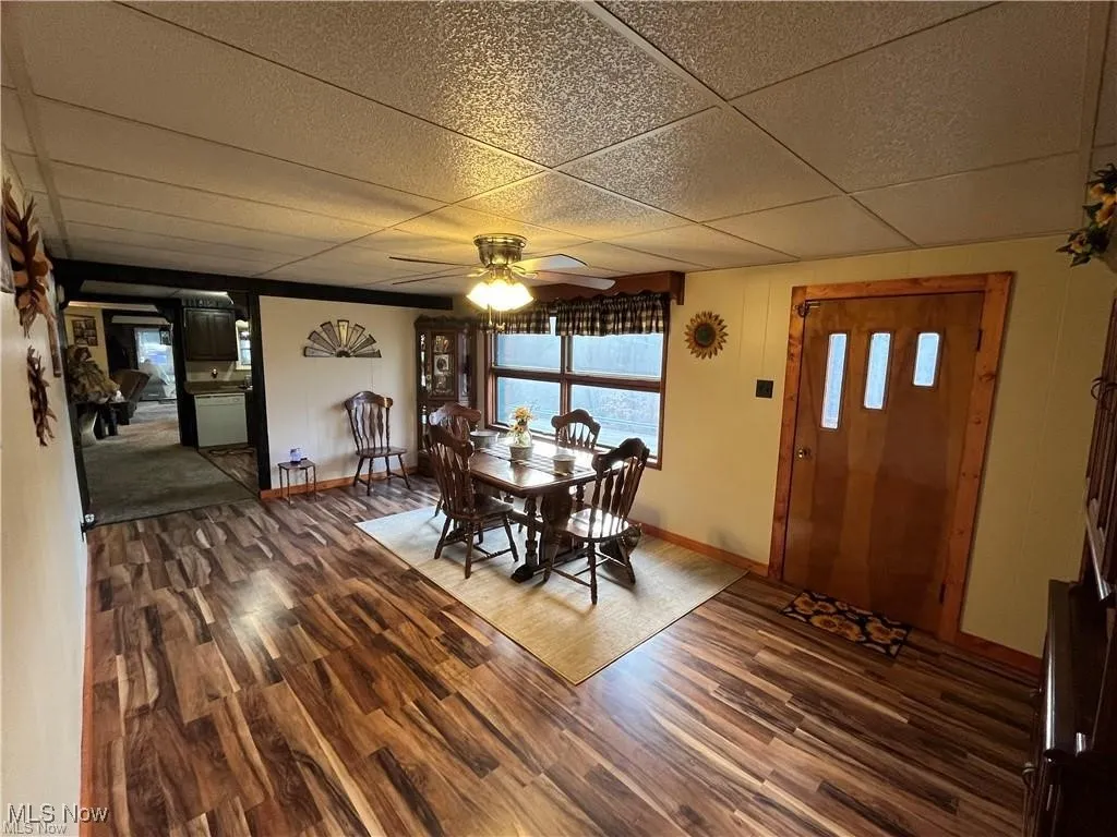Dining room featuring a drop ceiling, wood finished floors, baseboards, and a ceiling fan