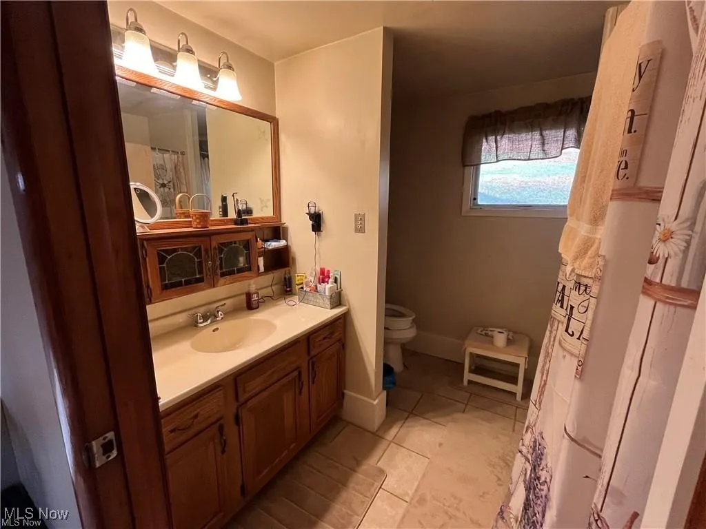 Bathroom featuring toilet, tile patterned flooring, and vanity