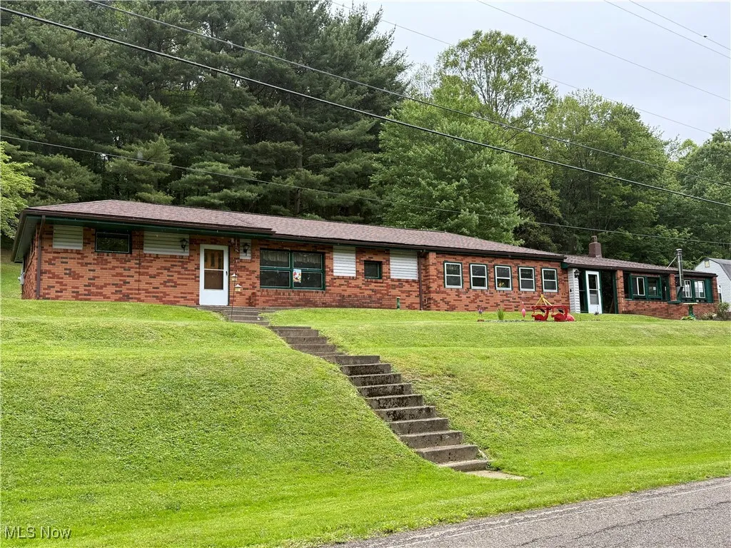 Ranch-style home with brick siding, a front lawn, and a chimney