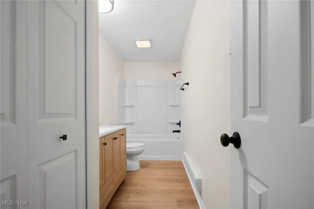 Bathroom with vanity, wood finished floors, shower / tub combination, baseboards, and toilet