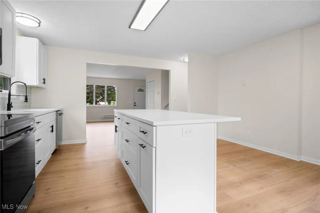 Kitchen featuring stainless steel range with electric cooktop, a sink, light wood finished floors, and light countertops