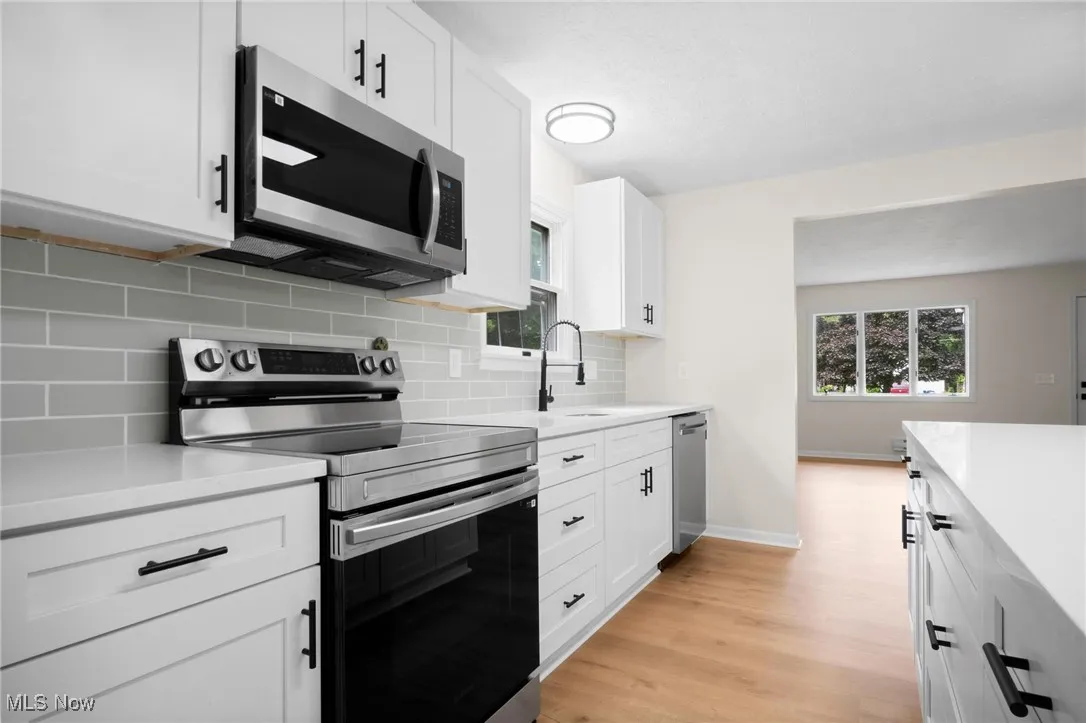 Kitchen with stainless steel appliances, a sink, decorative backsplash, and light countertops