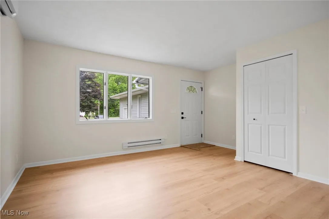 Foyer with baseboard heating, light wood finished floors, and baseboards