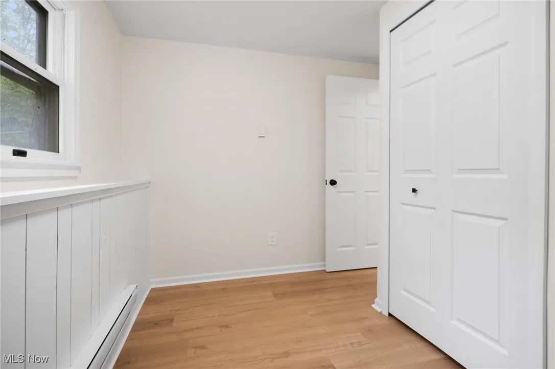 Hall with baseboard heating, light wood-style flooring, and baseboards