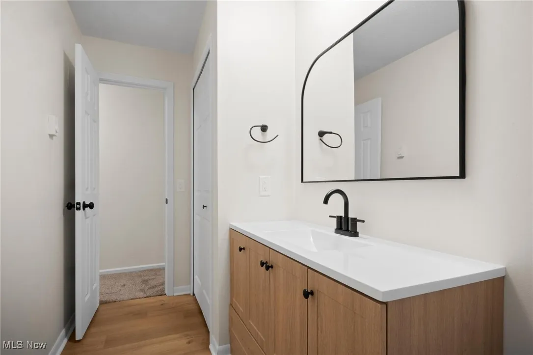 Bathroom featuring wood finished floors, vanity, and baseboards