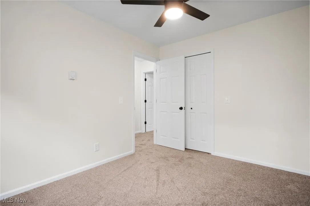 Unfurnished bedroom with carpet, baseboards, a closet, and a ceiling fan