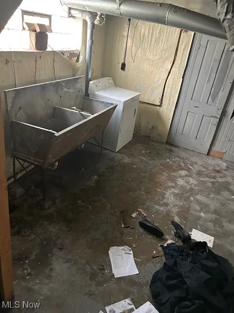 Unfinished below grade area featuring washer / clothes dryer and a sink