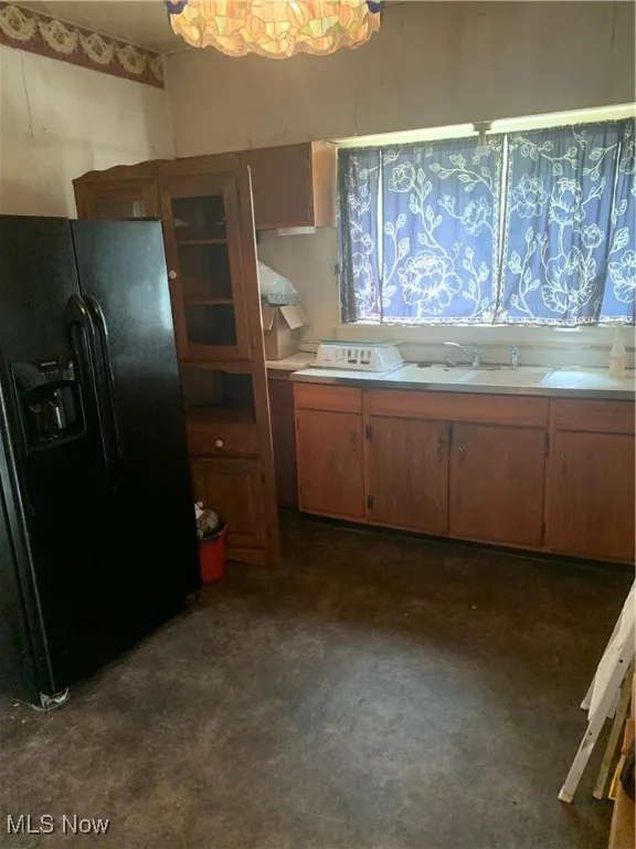 Kitchen featuring fridge, light countertops, and brown cabinetry