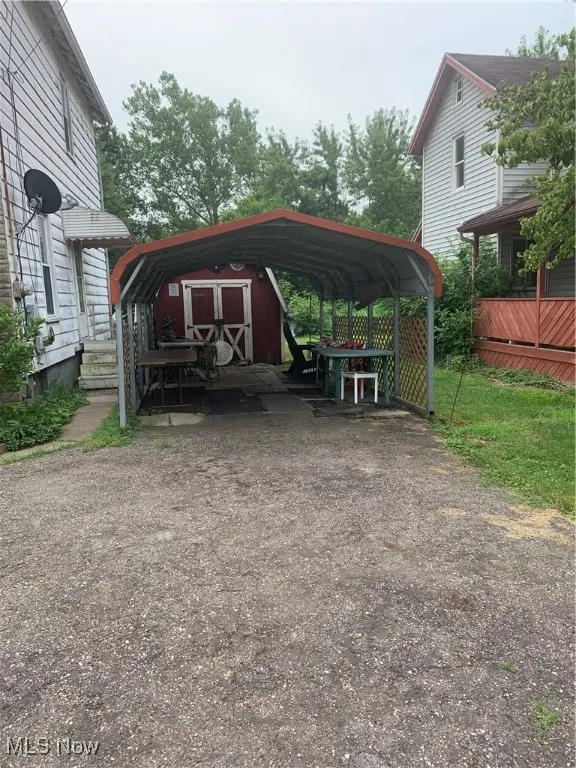 View of parking with a detached carport, a shed, and driveway