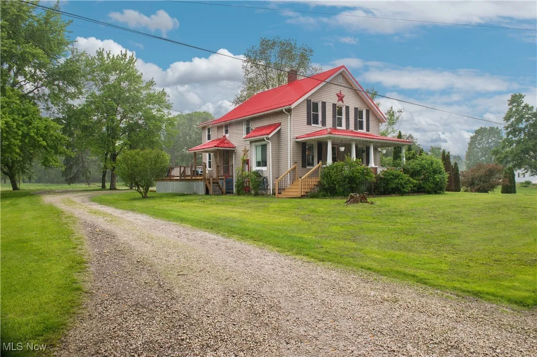 View of front facade featuring a front yard, a chimney, metal roof, and driveway