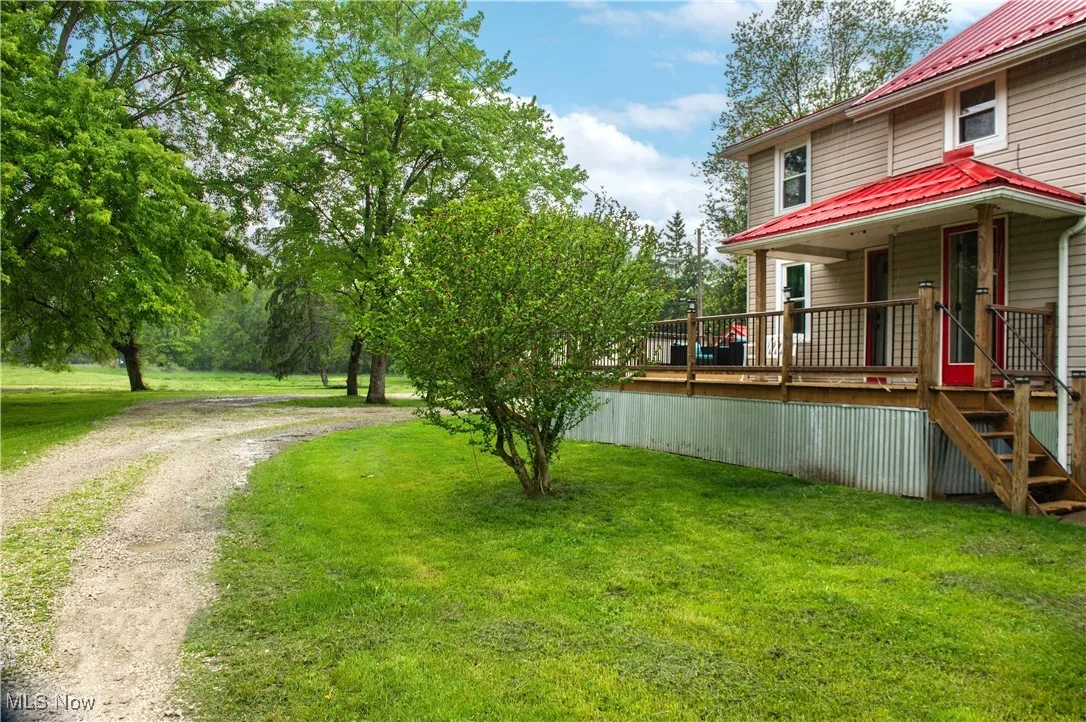 View of grassy yard featuring driveway and a wooden deck