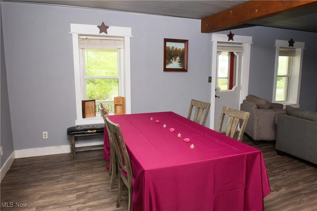 Rec room featuring plenty of natural light, dark wood-style flooring, baseboards, and beam ceiling