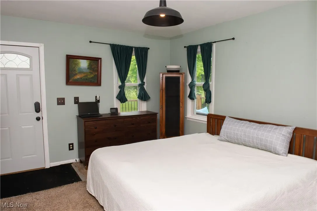 Carpeted bedroom featuring multiple windows and baseboards