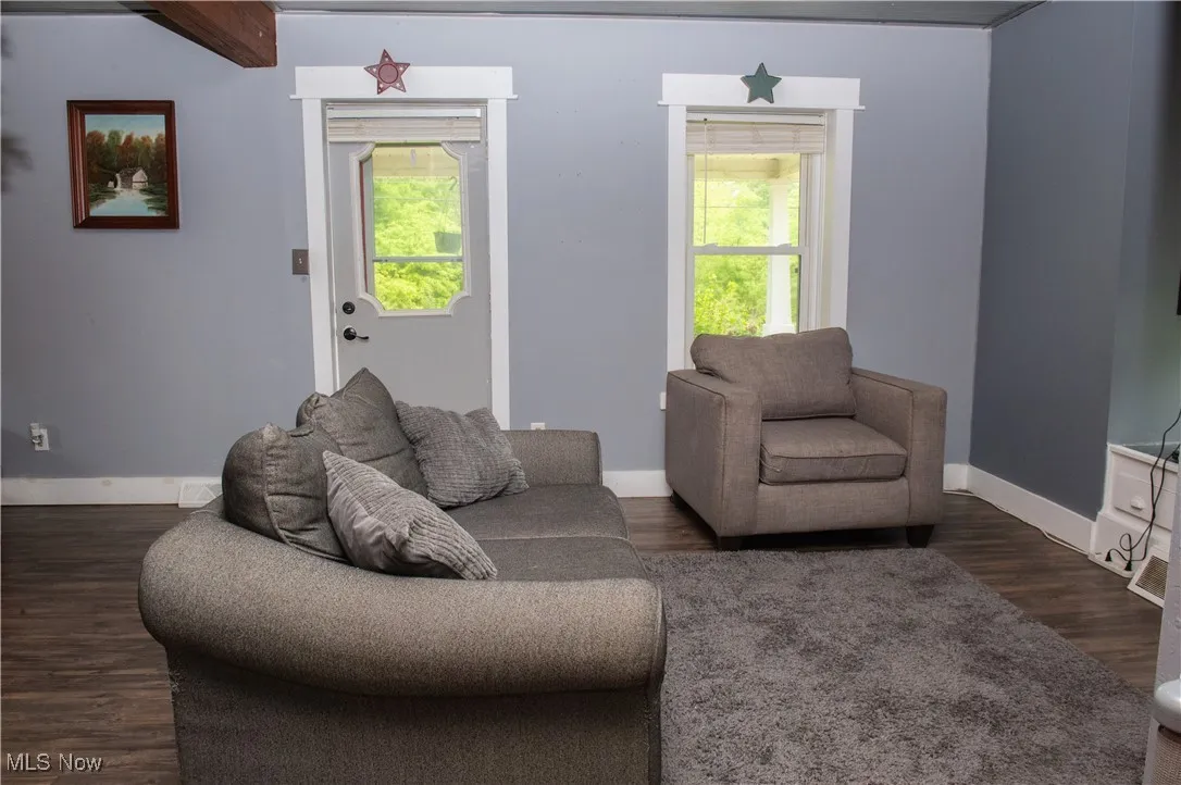 Living area featuring healthy amount of natural light, baseboards, and dark wood-style flooring