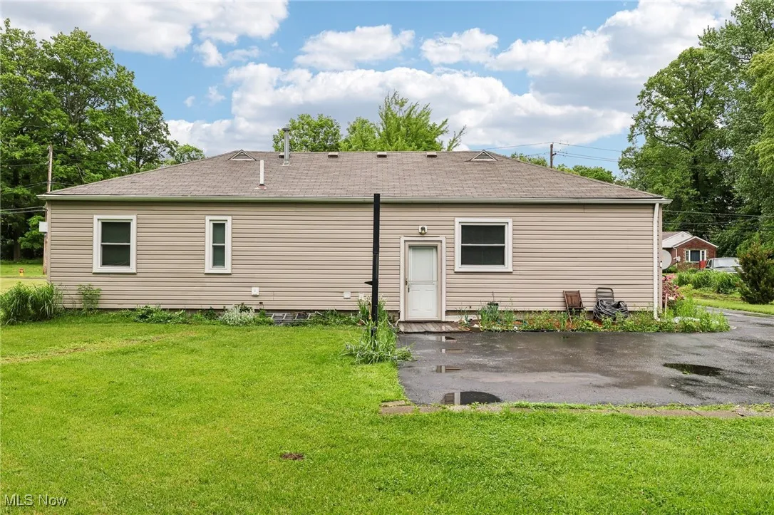 Back of property with a yard, a patio, and roof with shingles