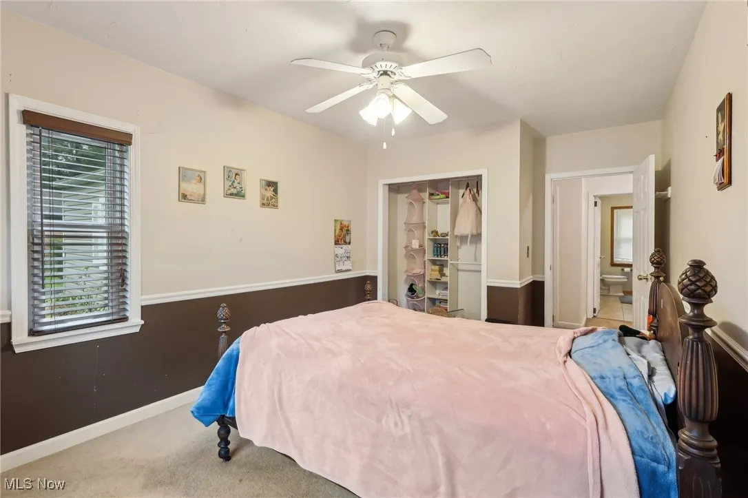 Carpeted bedroom featuring multiple windows, ceiling fan, baseboards, and a closet